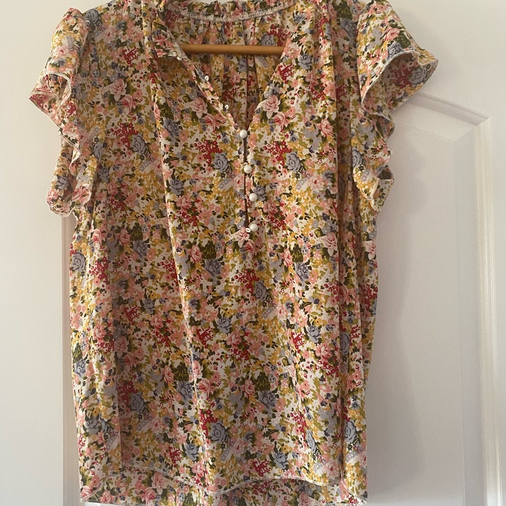 Floral top with buttons in the front.  Ruffles on shoulders.